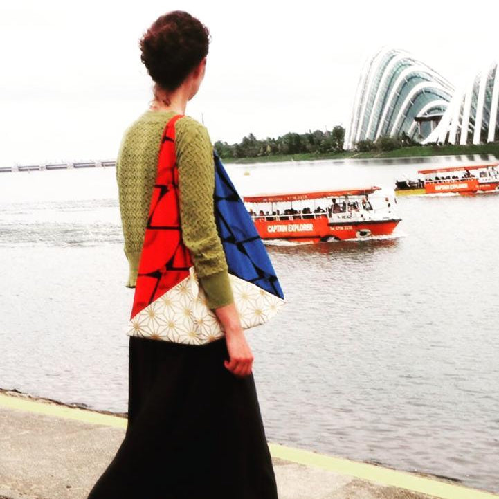 Person standing by a waterfront with futuristic architecture in the background